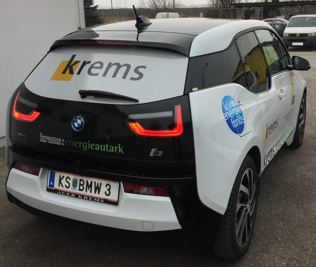 Foto eines Elektro-Autos mit diversen Beklebungen. So zum Beispiel: krems: energieautark, Klimaenergiefond, Klima- und Energiemodellregion, Krems